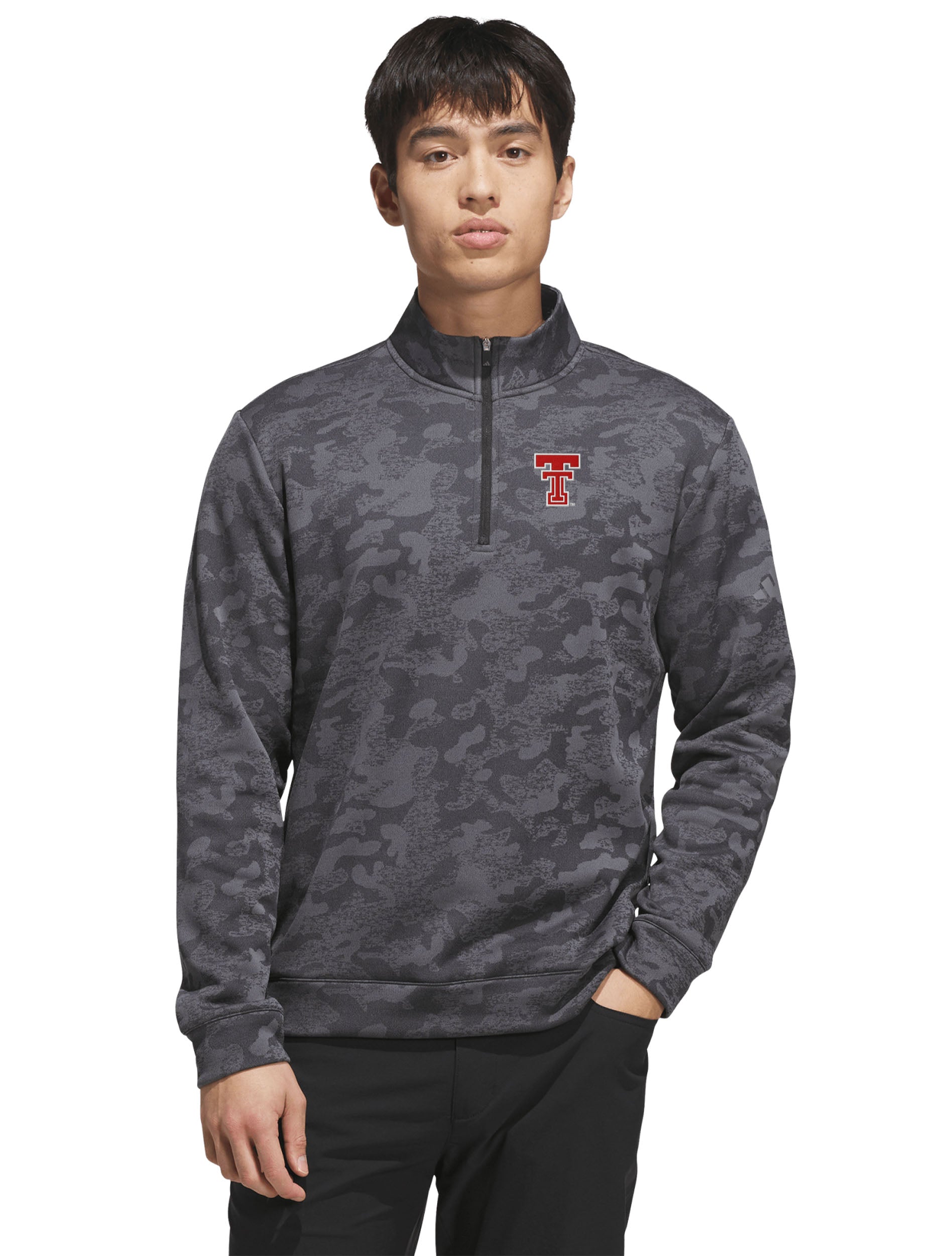 Model wearing the tonal camo golf quarter zip over black pants