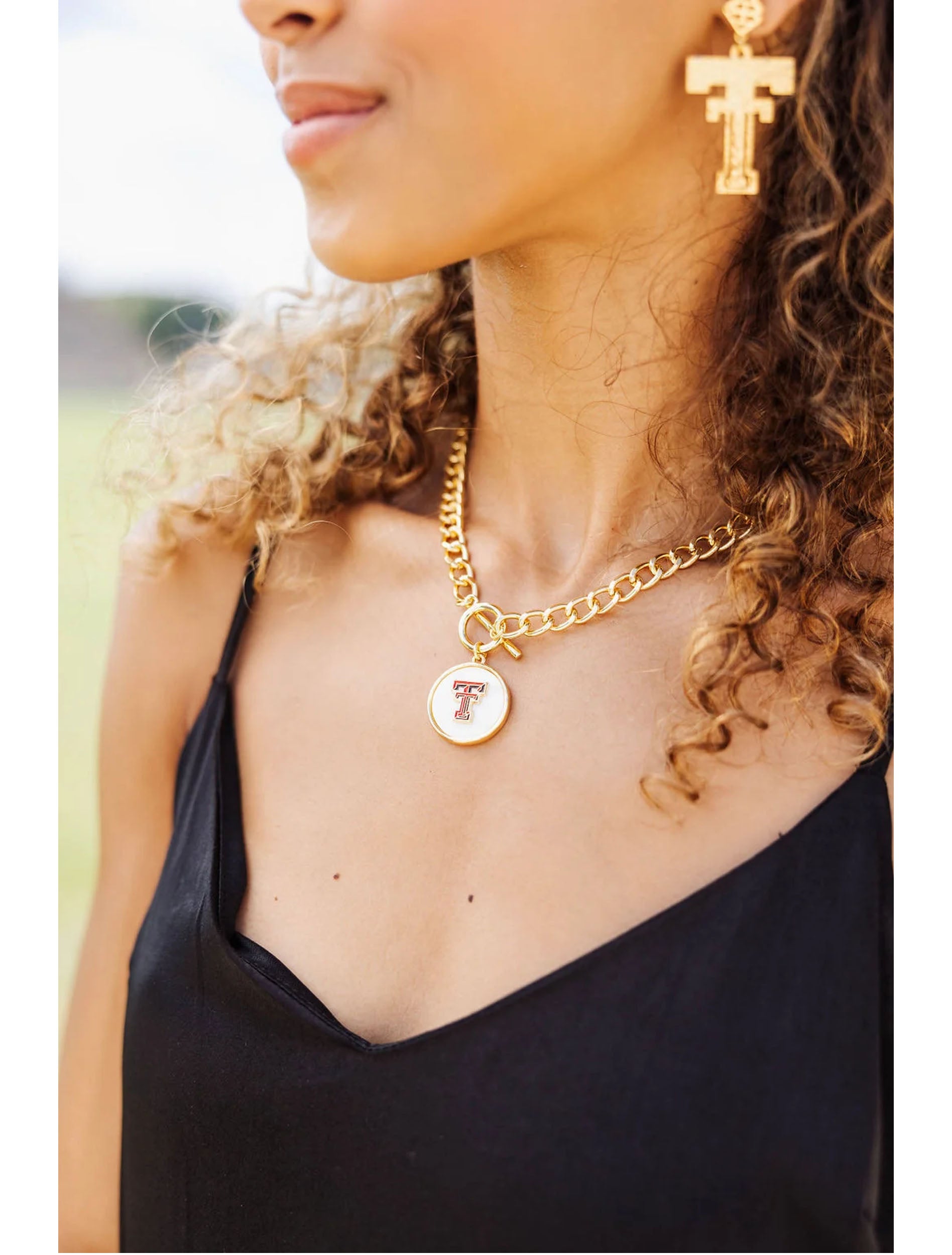 Model wearing the gold Texas Tech Double T toggle necklace with a black top and gold Double T earrings