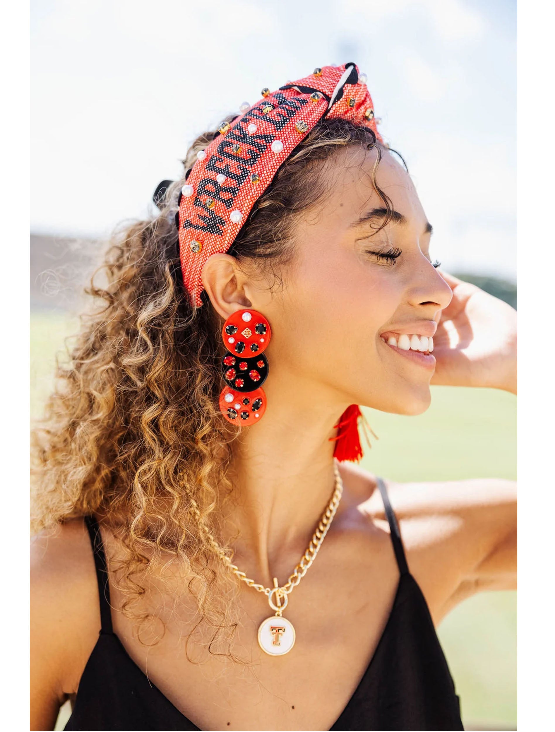 Model wearing the gold Texas Tech Double T toggle necklace with a red Wreck Em headband and beaded earrings