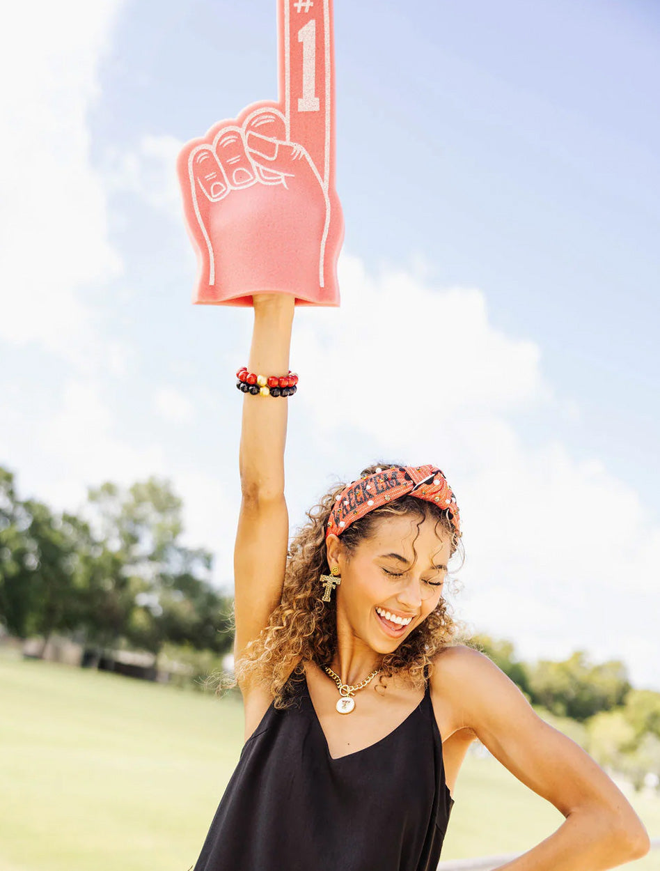 Model raising a foam finger while wearing the red Texas Tech “Wreck ’Em Tech” cross stitch headband