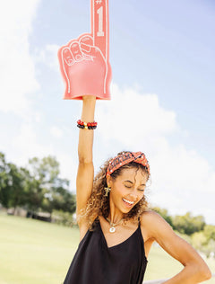 Model raising a foam finger while wearing the red Texas Tech “Wreck ’Em Tech” cross stitch headband
