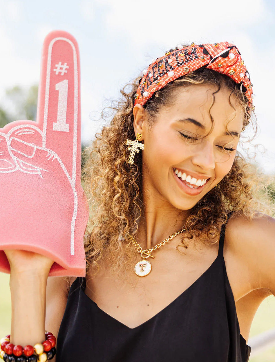 Model wearing the red Texas Tech “Wreck ’Em Tech” cross stitch headband and holding a foam finger