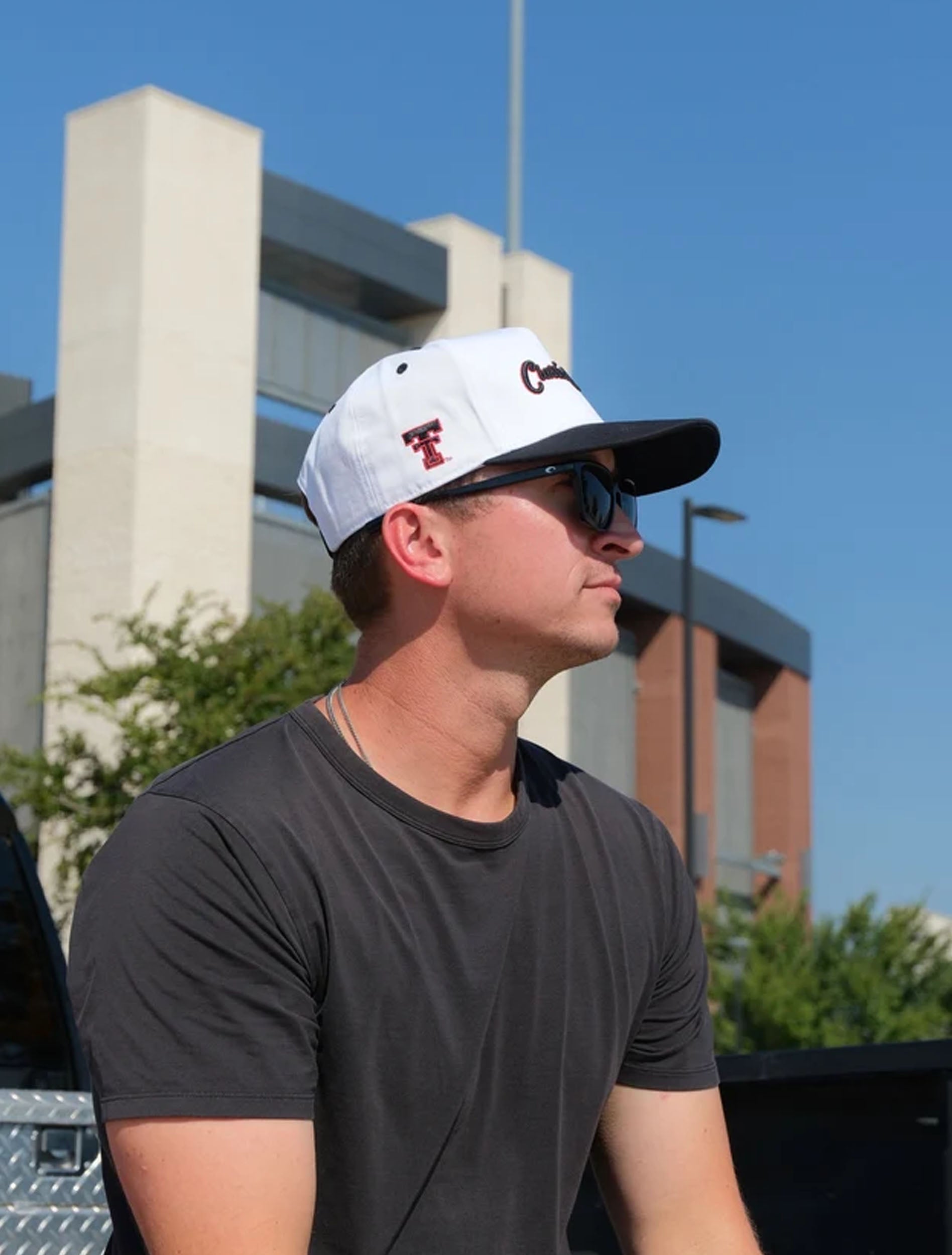 Man outdoors wearing the white Texas Tech cap with a black brim