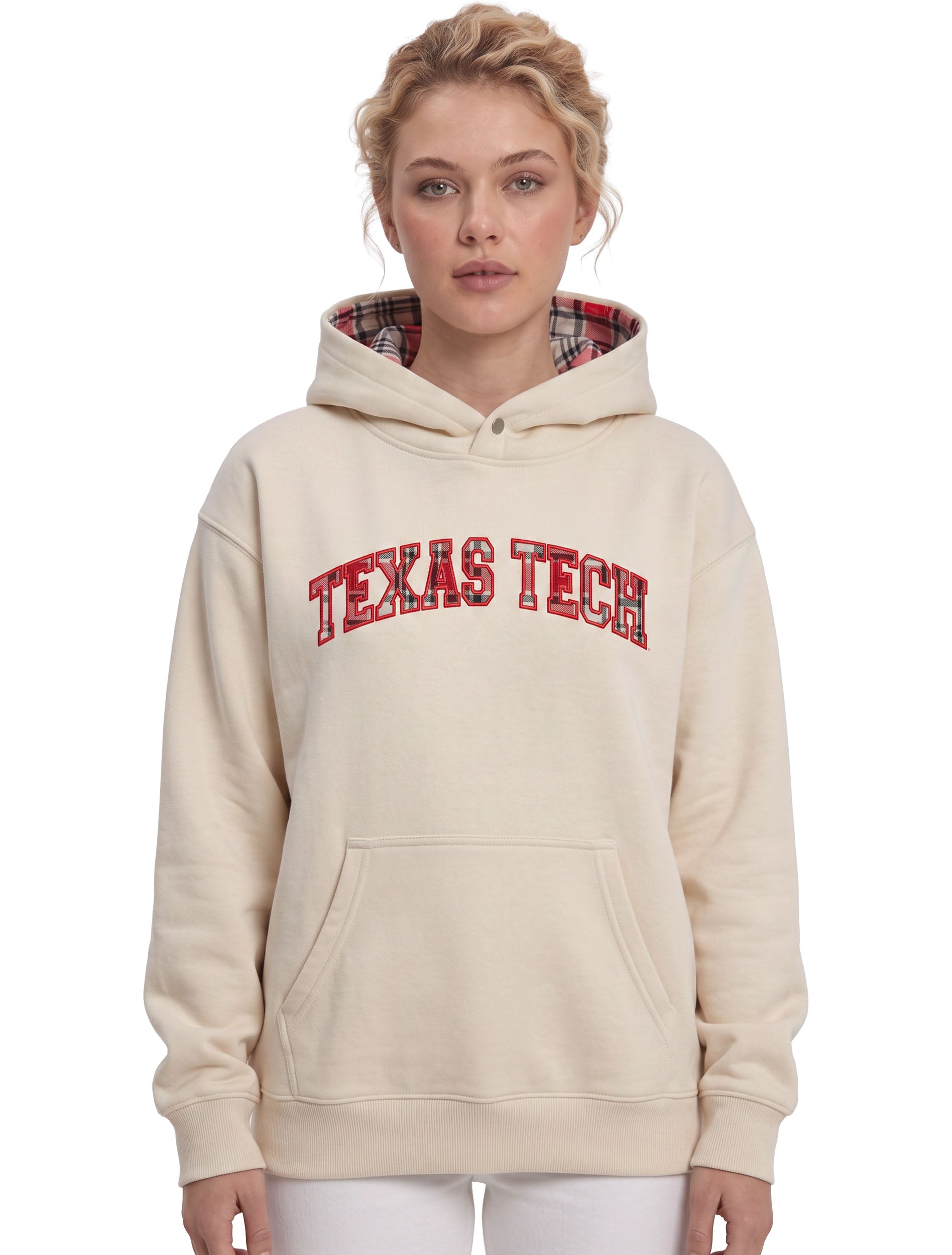 Model wearing the ivory Texas Tech hoodie with TEXAS TECH arched across the chest in red outlined plaid letters, a plaid lined hood and a metal snap at the neck