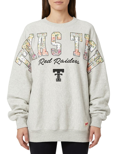 Model wearing the grey Pressbox Texas Tech Hilda BMOC oversized crew fleece with floral patchwork TEXAS TECH lettering, Red Raiders script and a black Double T