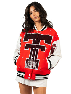 Close view of the red bomber jacket showing the sequin throwback Double T, silver snap front, and black and white striped ribbed collar and hem