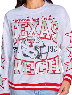 Close-up of wreck 'em tech script, iridescent appliqué letters outlined in red and a sequin helmet with a red Double T