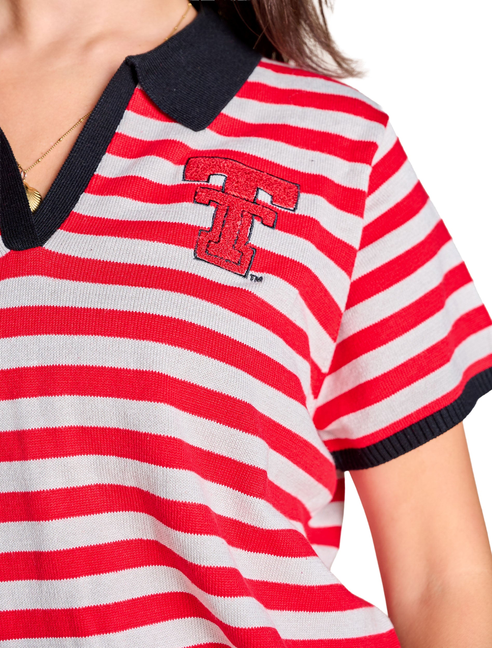 Close up of the red chenille Double T with black outline embroidery at the left chest, set against the red and white striped knit
