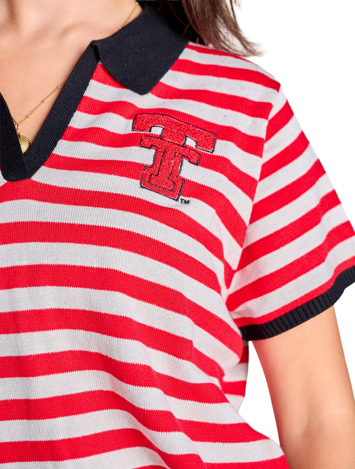 Close up of the red chenille Double T with black outline embroidery at the left chest, set against the red and white striped knit