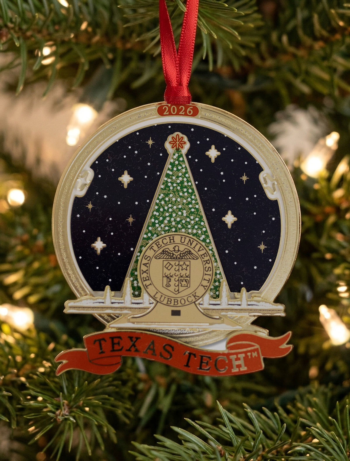 Texas Tech 2026 Carol of Lights ornament hanging from a red ribbon on a lit Christmas tree