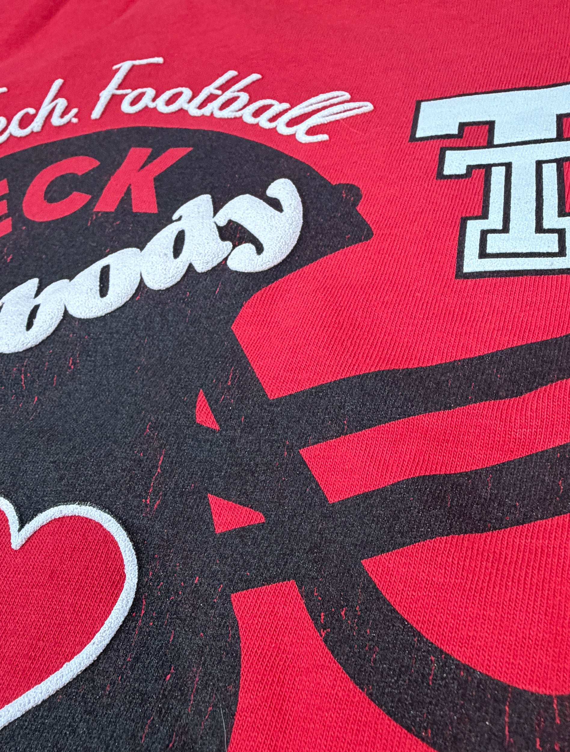 Close up of the raised white puff print lettering and the red heart on the helmet