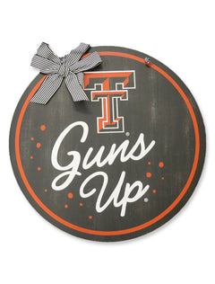 Black round wood door hanger with a red ring border, the Double T above Guns Up in white script, and a black and white striped ribbon bow